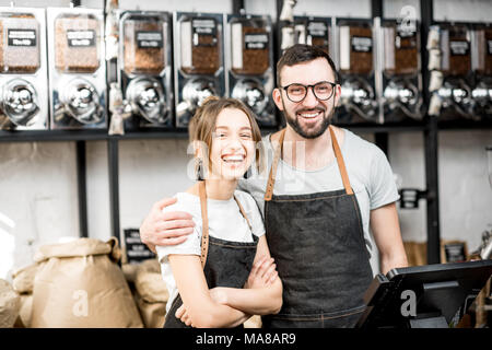 Portrait of a young couple of baristas standing together at the counter of the coffee store Stock Photo