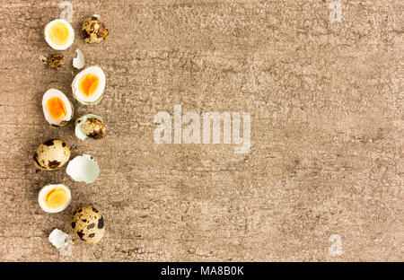 Top view of whole, shelled and Halved quail eggs on brown background with lots of copy space. Stock Photo