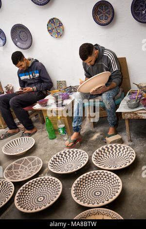 Morocco, Fes, Quartier des Potiers, Pottery, workers hand decorating geometric patterned dishes Stock Photo
