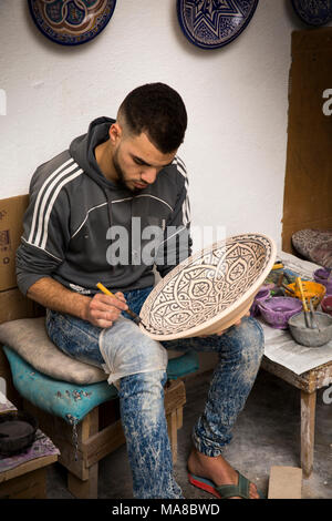 Morocco, Fes, Quartier des Potiers, Pottery, worker hand decorating geometric patterned dish Stock Photo