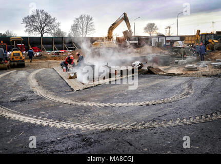 A worker cuts concrete curb circular saw at a construction site Stock Photo
