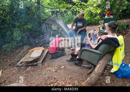 People sit around a small fireplace outside one of the self-built lowimpact homes in the Runnymed Eco village. The Village had planned a three day Festival For Democracy to celebrate the 800th anniversary of Magna Carta, signed close to their site, and to explore how UK citizens can write a Magna Carta for the 21st century.  Police surrounded the site, preventing people from entering and issuing exclusion notices for the surrounding area to prevent it taking place, and shortly after the villagers were evicted and the properties destroyed. Stock Photo