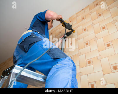 Voronezh, Russia - May 13, 2017: Worker drills holes in the wall with a perforator Stock Photo