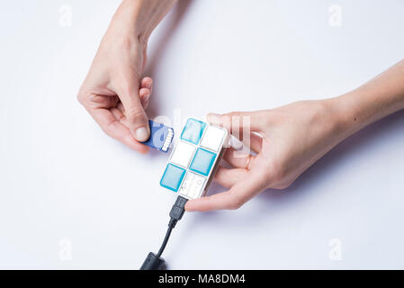 Hands of a girl inserting a memory card into a card reader on a white background Stock Photo