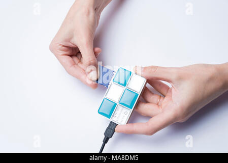 Hands of a girl inserting a memory card into a card reader on a white background Stock Photo