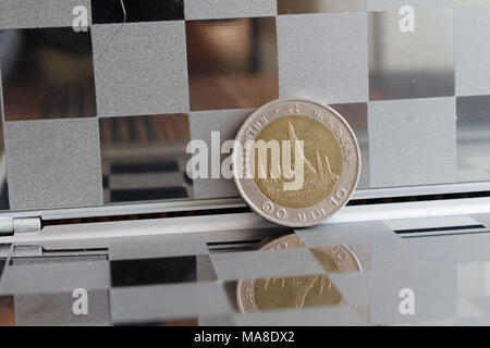 Thai coin in mirror reflect wallet lies on wooden bamboo table background Denomination is ten baht Stock Photo