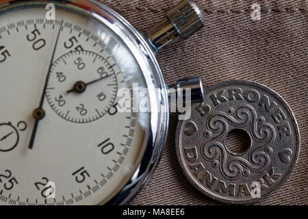 Denmark coin with a denomination of five krone (crown) and stopwatch on beige denim backdrop - business background Stock Photo