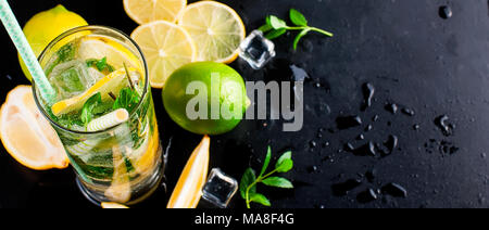 Top view of mojito cocktail, ice cubes and  cocktail ingredients on black slate board, cocktail drinks concept. Banner. Stock Photo