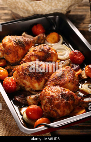 Roasted chicken legs with vegetables on wooden background Stock Photo