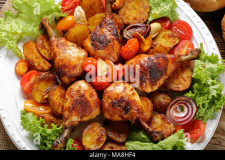 Roasted chicken legs with baked potato on the plate Stock Photo
