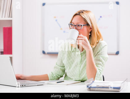 Businesswoman is working and drinking coffee in her office. Stock Photo