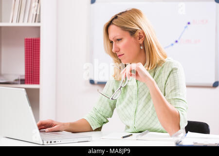 Businesswoman is working on laptop in her office. Stock Photo
