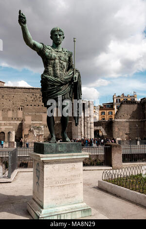 Statue of roman emperor Caesar Augustus on Via dei Fori Imperiali, Rome with the Forum of Augustus in the background Stock Photo