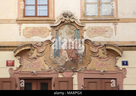 Baroque house sign on the House at the Black Ox (Dům u Černého vola) in Loretánské Square in Hradčany district in Prague, Czech Republic. Saint Luke the Evangelist is depicted in the house sign as he showing the icon to the Virgin Mary. The famous authentic Pub at the Black Ox (Hospoda u Černého vola) is located in this house. Stock Photo