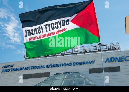A Palestinian flag from Inminds with the message 'Boycott Israel' flying in front of Excel London at Stop 4S protest outside G4S AGM. The centre is owned by the Abu Dhabi National Exhibitions Company ADNEC. Stock Photo