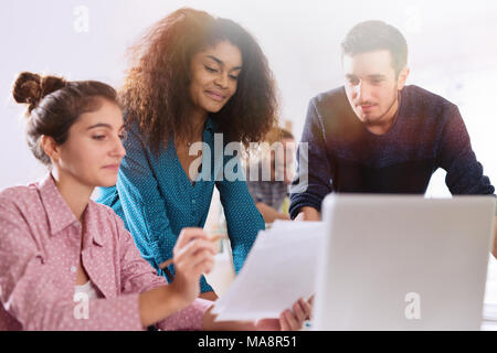 At office. A young multi-ethnic work team exchanges ideas ar Stock Photo