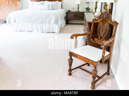 Bright white modern wooden rocking chair in nursery room bedroom with chest of drawers, bed, decorations in model staging home, apartment or house Stock Photo