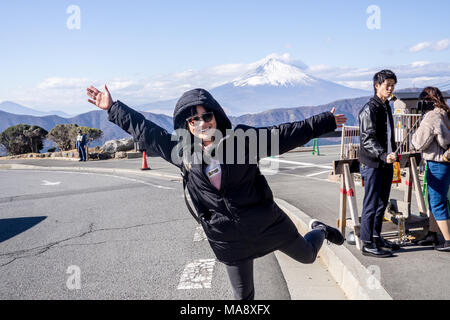 Happy female traveller posing with Mount Fuji from Owakudani on Mount Hakone in the background Stock Photo