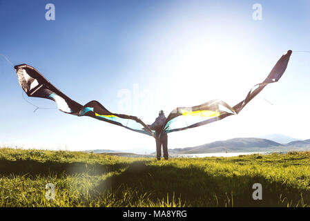 Man woman stands with kite in sun light Stock Photo