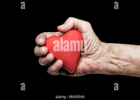 Red heart in senior hand over black background Stock Photo