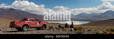 Young couple travellers in a mountain landscape on a 4x4 tour and camping in South America, enjoying the views at breakfast on Laguna Verde from the f Stock Photo