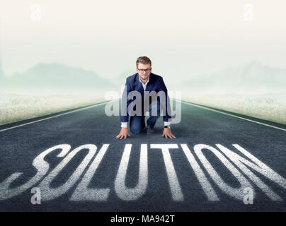 Young determined businessman kneeling before solution text Stock Photo