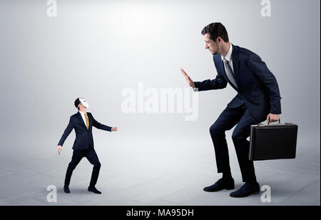 Conflict between small masked businessman and big elegant businessman  Stock Photo