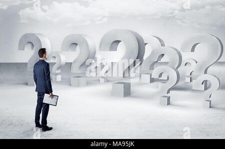 Businessman standing and looking to a bunch of question mark signs  Stock Photo