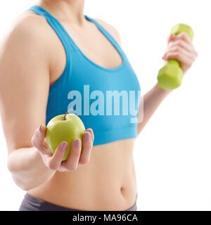 Young woman holding apple and hand weight, studio shot. Stock Photo