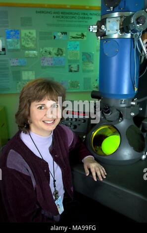 Cynthia Goldsmith, a Centers for Disease Control (CDC) research biologist, sitting in front of a transmission electron microscope (TEM), 2004. Image courtesy Centers for Disease Control. () Stock Photo