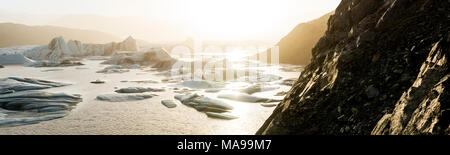Panoramic landscape at sunset at Hoffellsjökull outlet glacier which flows from the ice cap of Vatnajökull, with black rock carved out sides. It is lo Stock Photo