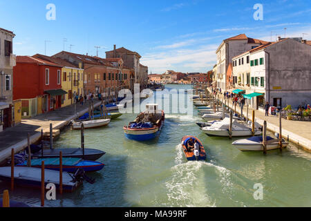 Murano, Italy - October 07, 2017: View across San Donato channel with colorful houses, multiple moored boats and couple of small boats moving in the w Stock Photo
