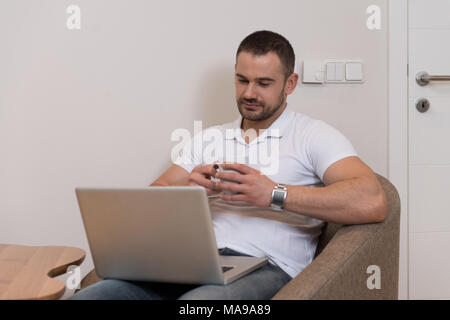 Handsome Man Sitting at Living Room Table Using Laptop Computer at Home Stock Photo
