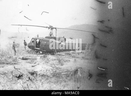 Black and white photograph showing two men, apparently pulling on ropes attached to a helicopter that is docked on a sandy or rocky landscape, photographed in Vietnam during the Vietnam War (1955-1975), 1971. ()
