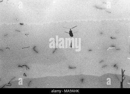 Black and white photograph showing a helicopter in mid-flight, with the sun in the background, photographed in Vietnam during the Vietnam War (1955-1975), 1971. ()