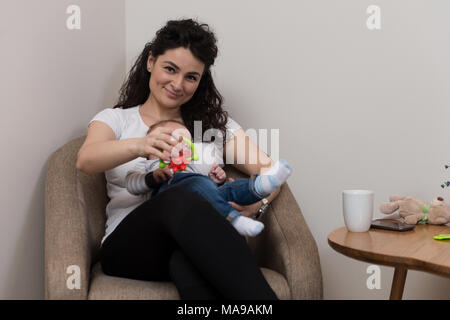 Happy Mother with Child Baby Boy at Home in the Living Room Playing and Laughing Stock Photo