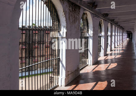 Long Corridor in Cellular Jail, Port Blair, Andaman Islands, India. Solitary confinement cells along the white wall of an old prison Stock Photo