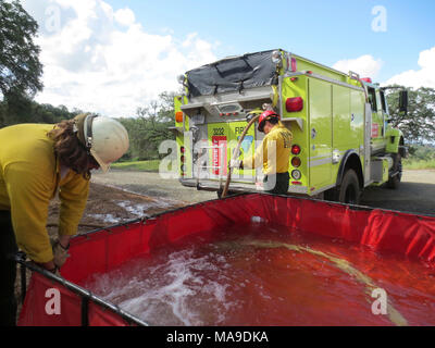 Portable Water Tank. Wildland firefighters fill a large portable water tank. These tanks are used primarily in rural areas where fire hydrants are not available. Stock Photo