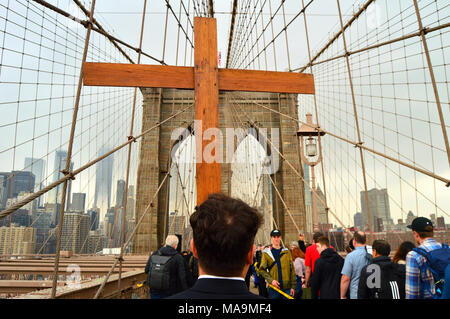 New York, NY, USA March 30, 2018 A young man carries a wooden cross across the Brooklyn Bridge, as part of a Good Friday procession in New York Credit: James Kirkikis/Alamy Live News Stock Photo