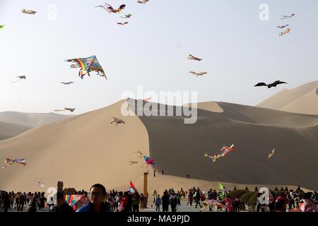 Dunhuang, China's Gansu province. 31st Mar, 2018. People fly kites at the scenic spot of the Crescent Spring, a crescent-shaped lake surrounded by deserts at the foot of the Mingsha Hill, in Dunhuang, northwest China's Gansu province, March 31, 2018. Credit: Zhang Xiaoliang/Xinhua/Alamy Live News Stock Photo