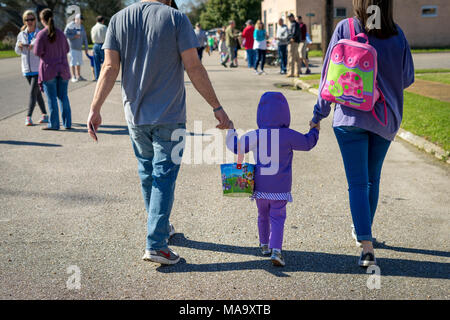 Alabama, USA, 31 Mar 2018. Micah West, center, walks with her parents as they get ready for the Easter Egg Hunt in downtown Vernon, Al. At least a hundred kids showed up on Saturday, March 31st 2018 for the event. Credit: Tim Thompson/Alamy Live News Stock Photo