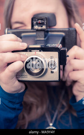 Teenage girl using an original Polaroid instant camera Stock Photo