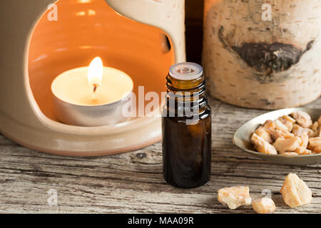 A bottle of styrax benzoin essential oil with benzoin resin and an aroma lamp Stock Photo