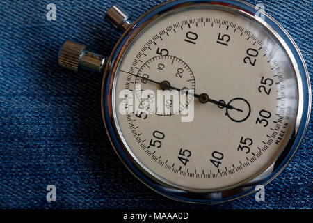 Stopwatch on worn blue jeans background, value measure time, old clock arrow minute and second accuracy timer record Stock Photo