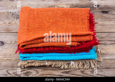 Stack of colored  burlap on wooden table. Studio Photo Stock Photo