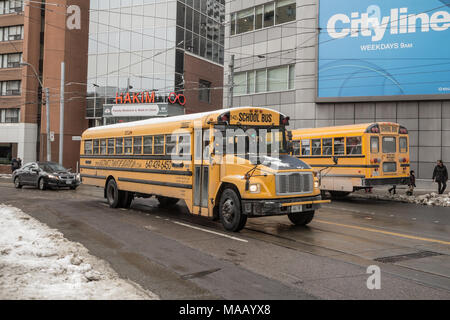 TORONTO, CANADA - DECEMBER 20, 2016: Freightliner FS 65 school bus on service in a residential part of downtown Toronto, another yellow school bus can Stock Photo