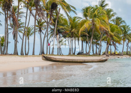 wooden canoe boat on beach with palm trees - Stock Photo