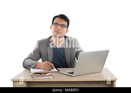 businessman writing notes on a writing pad while sitting at his desk behind his new notebook isolated on white background. Stock Photo