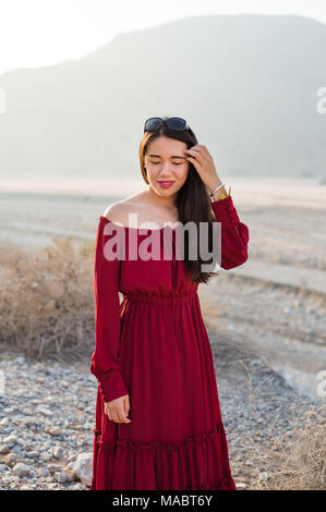 Beautiful girl wearing red dress in a dessert valley portrait Stock Photo