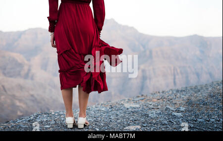Fashionable girl in red dress on a desert mountain top close up Stock Photo